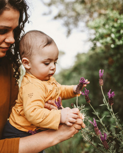 Humana Baby pflückt Blumen mit Mama