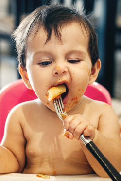 Humana süßes Baby isst Nudeln mit Gabel