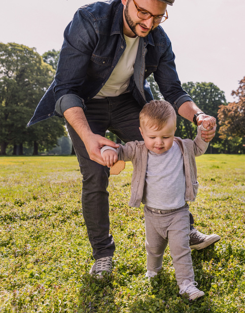 Humana Papa hilft Baby beim Laufen