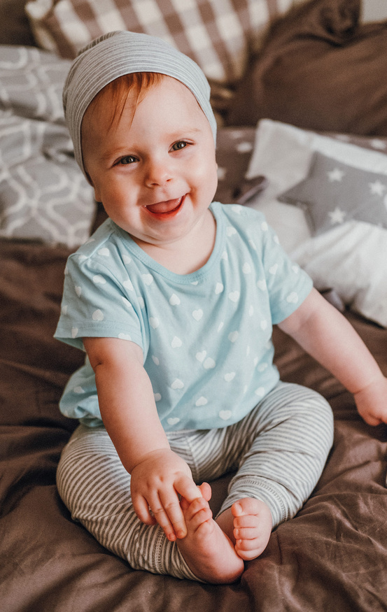 cute little happy baby girl plays sitting on a bed