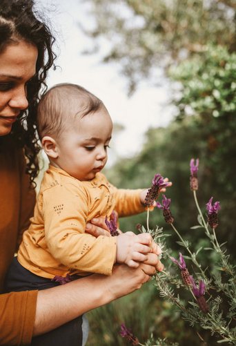 Humana Baby pflückt Blumen mit Mama