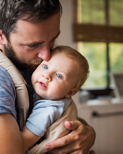 Humana Papa trägt Baby an seiner Brust