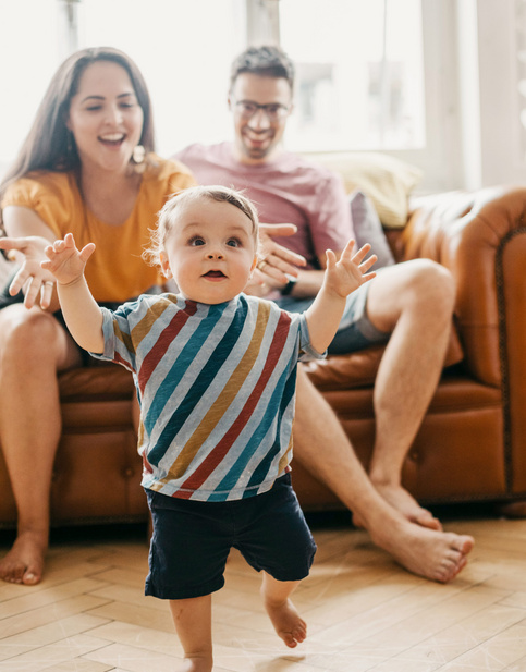 Humana Glückliche Eltern sehen Baby beim Laufen zu