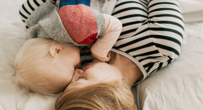 cute baby and mother cuddling on bed