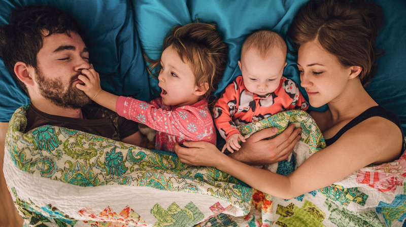 Humana Glückliche Familie liegt kuschelnd im Bett