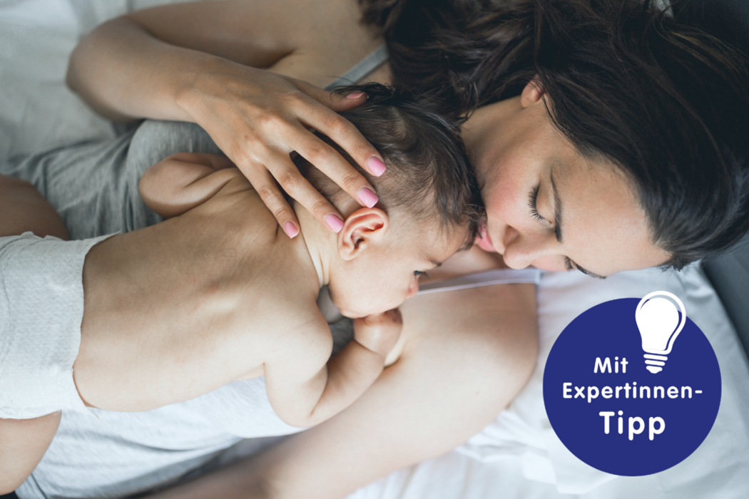 Mutter hält ihr schlafendes Baby in einem Bett und genießt einen zärtlichen Moment, umgeben von einer beruhigenden Atmosphäre.