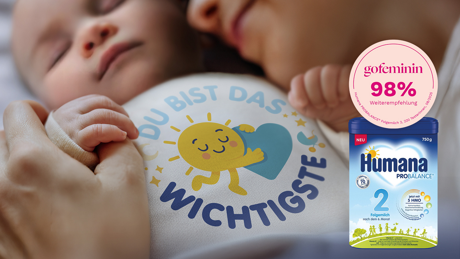 Schlafendes Baby in einem Body auf dem steht "Du bist das Wichtigste" und dessen Händchen den Daumen der Mama hält, deren Gesicht nahe am Baby liegt.